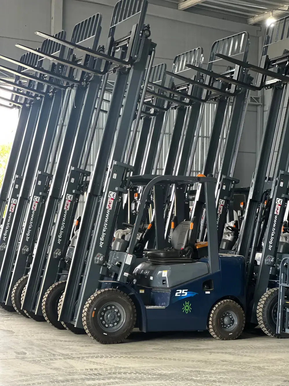 Empilhadeira TRIA em primeiro plano, com outras empilhadeiras alinhadas no galpão de estoque da Primetech
